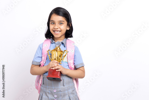 Foto Indian school girl in school uniform celebrating victory with trophy