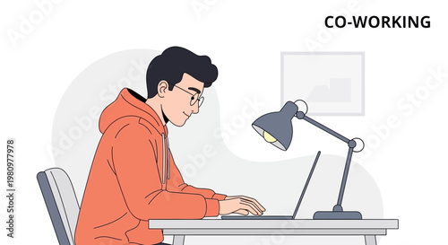 Young man working on laptop in cozy co-working space with desk lamp