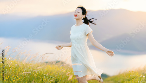 A joyful woman in a white dress enjoys a grassy hilltop at sunrise, embracing nature with open arms and a peaceful smile.