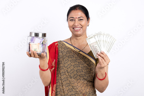 Fotografía Indian happy rural woman holding indian rupees 
and money jar on white backgroun