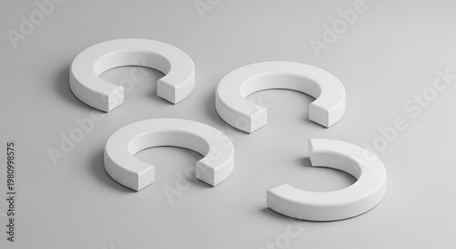 A minimalist arrangement of four white, horseshoe-shaped objects rests on a smooth, light gray surface.