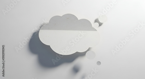 A minimalist, white thought bubble casts a soft shadow on a light gray wall, evoking contemplation and ideas.