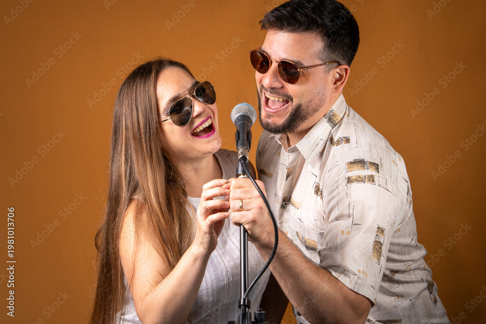 Obraz premium Pareja de hombre y mujer divirtiendose cantando juntos con un micrófono