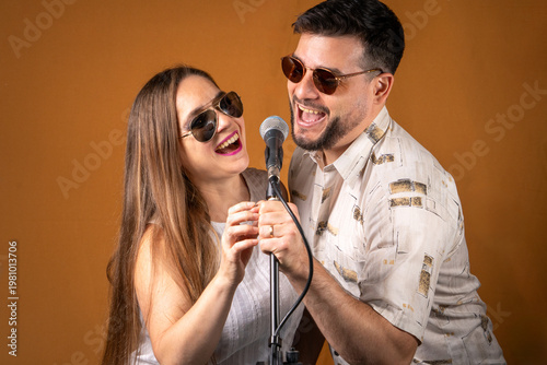 Pareja de hombre y mujer divirtiendose cantando juntos con un micrófono