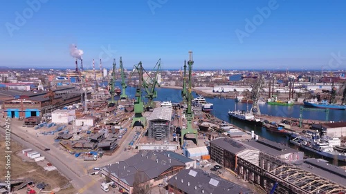 Luxury yacht construction in Gdansk shipyard with industrial cranes and maritime logistics infrastructure
