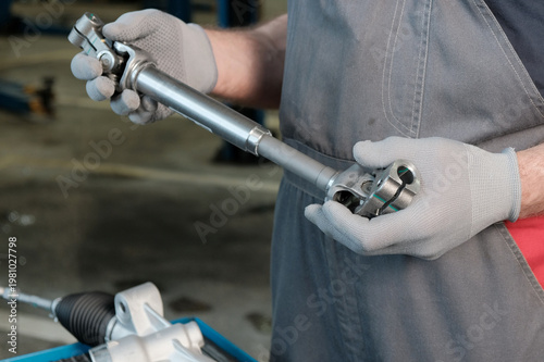 Installing a new steering rack.An auto mechanic prepares the steering rack for installation. Inspection of the new steering driveshaft, checking the compatibility of the control unit parts.