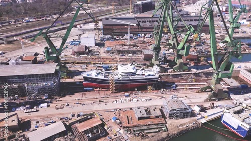 Modern Yaht in dry dock with industrial shipyard cranes for maintenance and maritime logistics