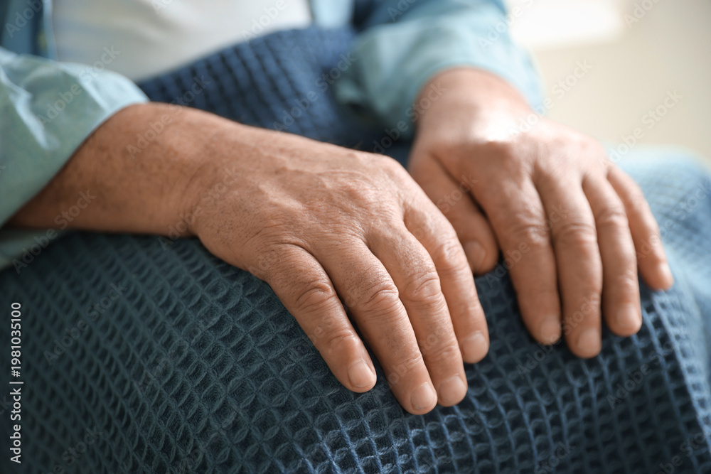Fototapeta premium Elderly man covering with blue blanket against blurred background, closeup