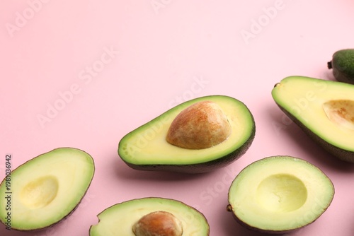 Many cut fresh avocados on pink background, closeup. Space for text