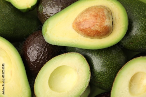 Fresh and cut avocados as background, top view