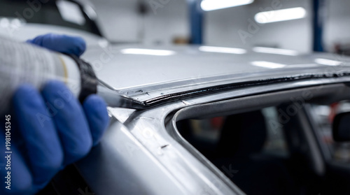 Auto worker applying sealant during car windshield replacement
