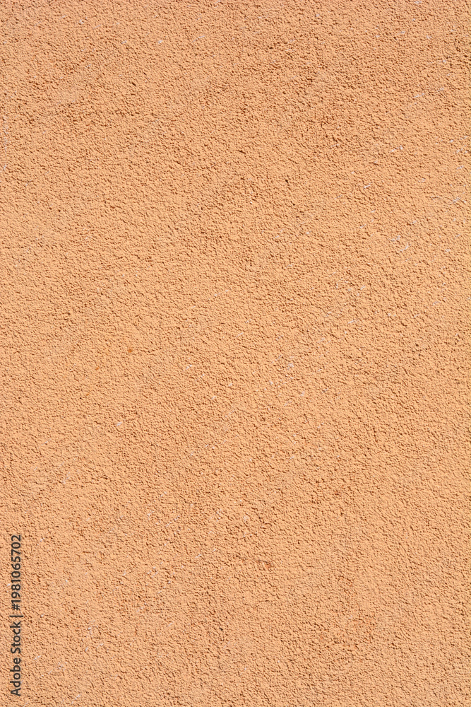 Fototapeta premium Rough texture of a pastel apricot stucco wall with a uniform sandy finish suitable for architectural or construction backgrounds. 