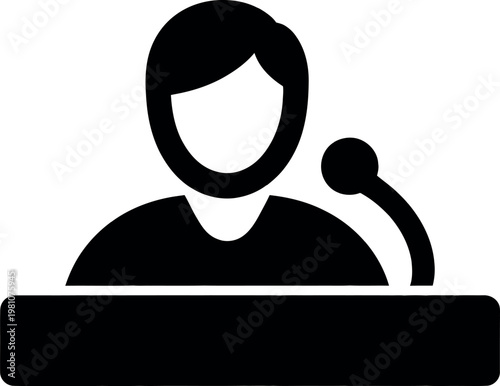 Person speaking at a microphone from behind a podium desk