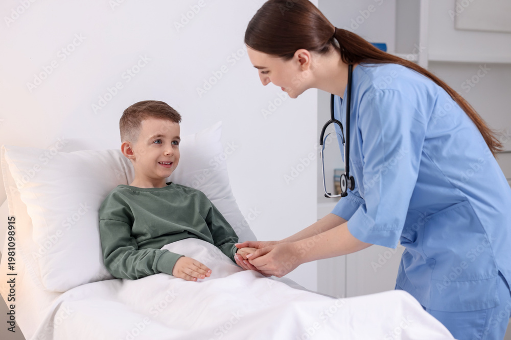 Fototapeta premium Doctor examining little child on bed in hospital