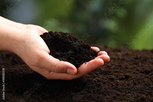 Woman with fresh soil on blurred background, closeup