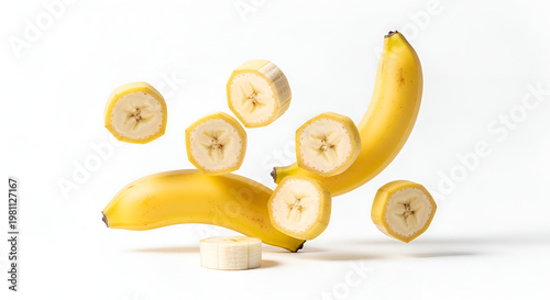 A vibrant yellow banana is artfully arranged with several sliced pieces suspended in mid-air against a clean white background, creating a playful and dynamic composition.