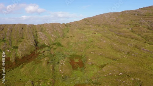 Wallpaper Mural Wide aerial drone shot of green mountains and rolling hills with rocky outcrops under a blue sky with light clouds. Torontodigital.ca
