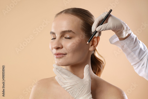 Photography Doctor drawing marks on patient's face against beige background, closeup
