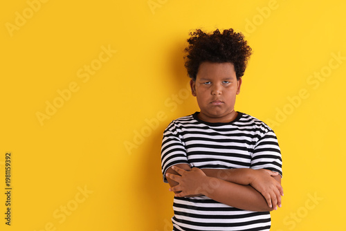 Foto Portrait of resentful little boy with crossed arms on yellow background