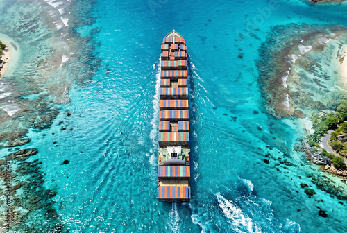 Cargo ship sailing through crystal clear tropical waters with vibrant colors and aerial perspective.