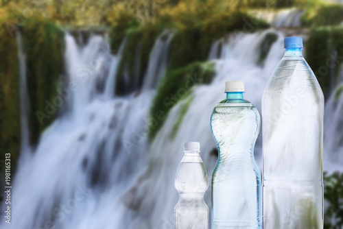 Pure water. Bottles against beautiful view on waterfall