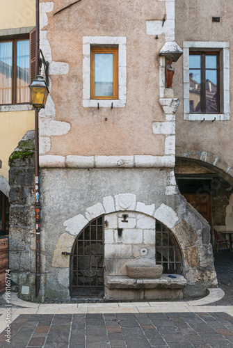 Old archway in Annecy, France, with water basin and glove in portrait format
