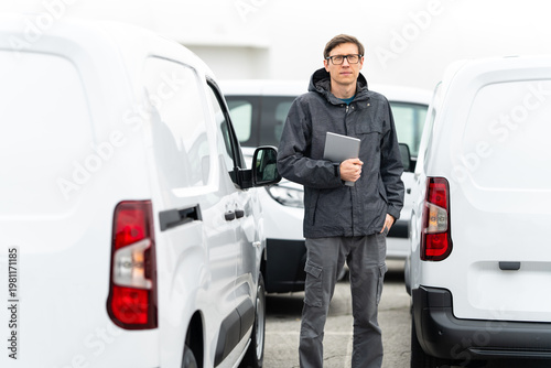 Wallpaper Mural Fleet manager with digital tablet supervising rows of white delivery vans Torontodigital.ca