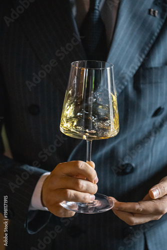 Sommelier swirling white wine in glass to release aroma in elegant tasting setting closeup