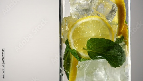 Fresh sparkling lemonade with lemon slices mint leaves and ice cubes in glass. Concepts of summer drink, themes for bars, cafes, and restaurants, refreshment, beverage, health.