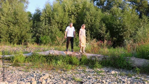 A couple slowly walks along a narrow path through tall grass during a long countryside walk