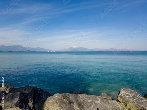 View of Lago di Garda from Desenzano del Garda, Italy, showing water and distant mountains under clear sky
