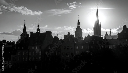 Silhouetted cityscape with spires piercing the sunlit sky, black and white