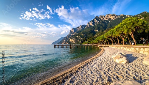 Serene lakeside scene with blue water, sandy beach, distant mountains and trees under a partly cloudy sky