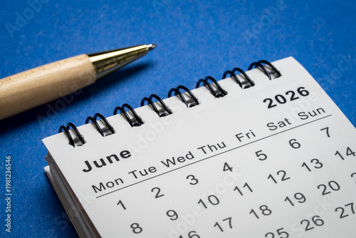 June 2026 - small spiral desktop calendar against art paper abstract, time and business concept