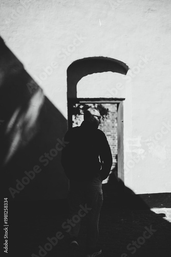 Foto Silhouette of man walking through arched doorway with strong light and shadow co
