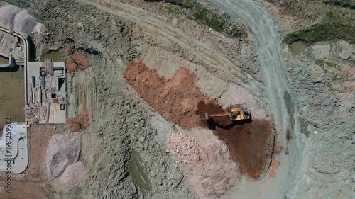 Drone view of an excavator working in a quarry. Industrial landscape, mining activity, heavy machinery, earthmoving process, top view of construction and extraction site.
