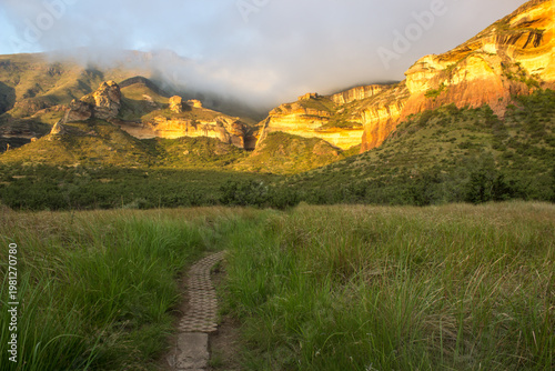 Obraz na plátne A path leading towards tall sandstone cliffs of the Drakensberg Mountains in the