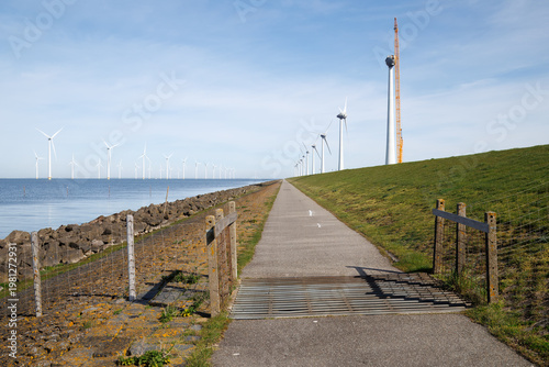 Wind turbines along dike with perspective towards horizon