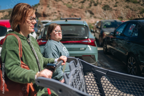 Woman pushing shopping cart with daughter having down syndrome