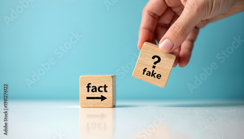 Hand holds wooden block with word fake and question mark over block with word fact and arrow. Concept of truth versus misinformation and decision.