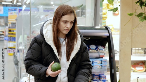 Konstfotografi Young woman in winter attire shopping for groceries in a supermarket produce sec