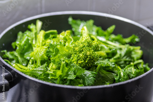 Washing cime di rapa, turnip greens, rapini or broccoli rabe in a bowl