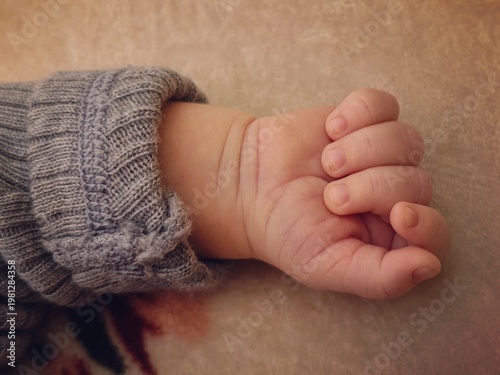 Baby Hand Close-Up – Soft Skin, Tiny Fingers and Cozy Sweater Sleeve – intimate detail of newborn in warm light