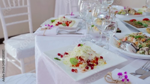 Refined dining table featuring pomegranate salad, surrounding dishes, empty glassware, silverware, presenting elegant culinary composition with sophisticated styling