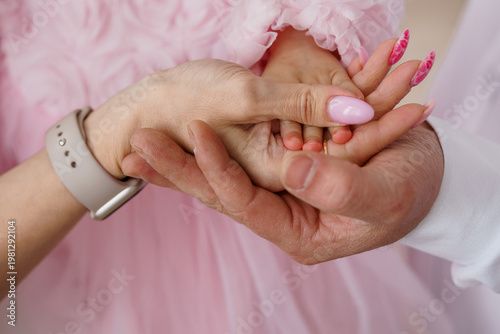 Canvas Print Close-up of adult hands gently holding a baby's tiny hand with pink manicured na