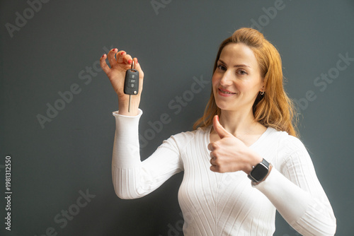 Happy Woman Holding Car Key Showing Thumbs Up. New Car Ownership Concept Description: