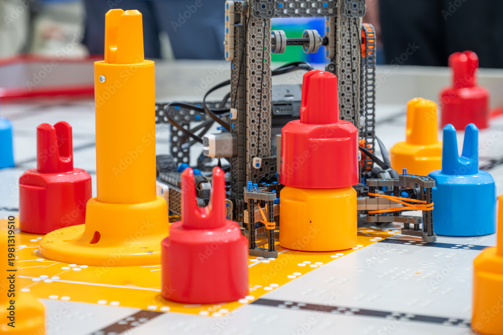 Fototapeta premium Robots and colorful game pieces are set on a table during a competition in a school hall in the afternoon