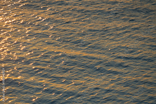 Foto Abstract blue water surface of the Baltic Sea with golden sunset reflections cre