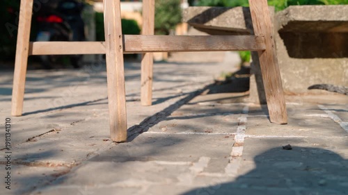 Shot from ground level, moving beneath a wooden stepladder across a cobblestone street, a perspective that transforms ordinary spaces into epic ones.