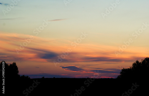 Sunset over the horizon with colorful sky and dark silhouettes of trees